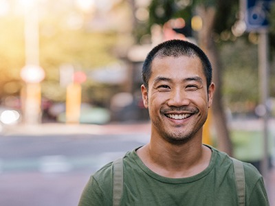 A young Asian man smiling confidently on a city street