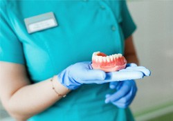 a dental hygienist holding a denture